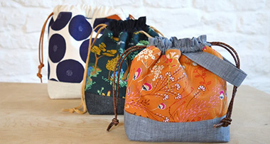 three drawstring bags sitting on a table in front of one another