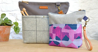 two knitting bags of different sizes sitting on a table next to a potted indoor plant