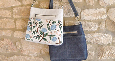 two crossbody purses handing on a stone wall