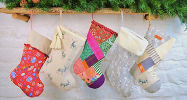 five Christmas stockings hanging from a wooden shelf 