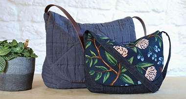 two different sizes of the Orla Purse in two patterns, on a wooden surface next to a potted plant